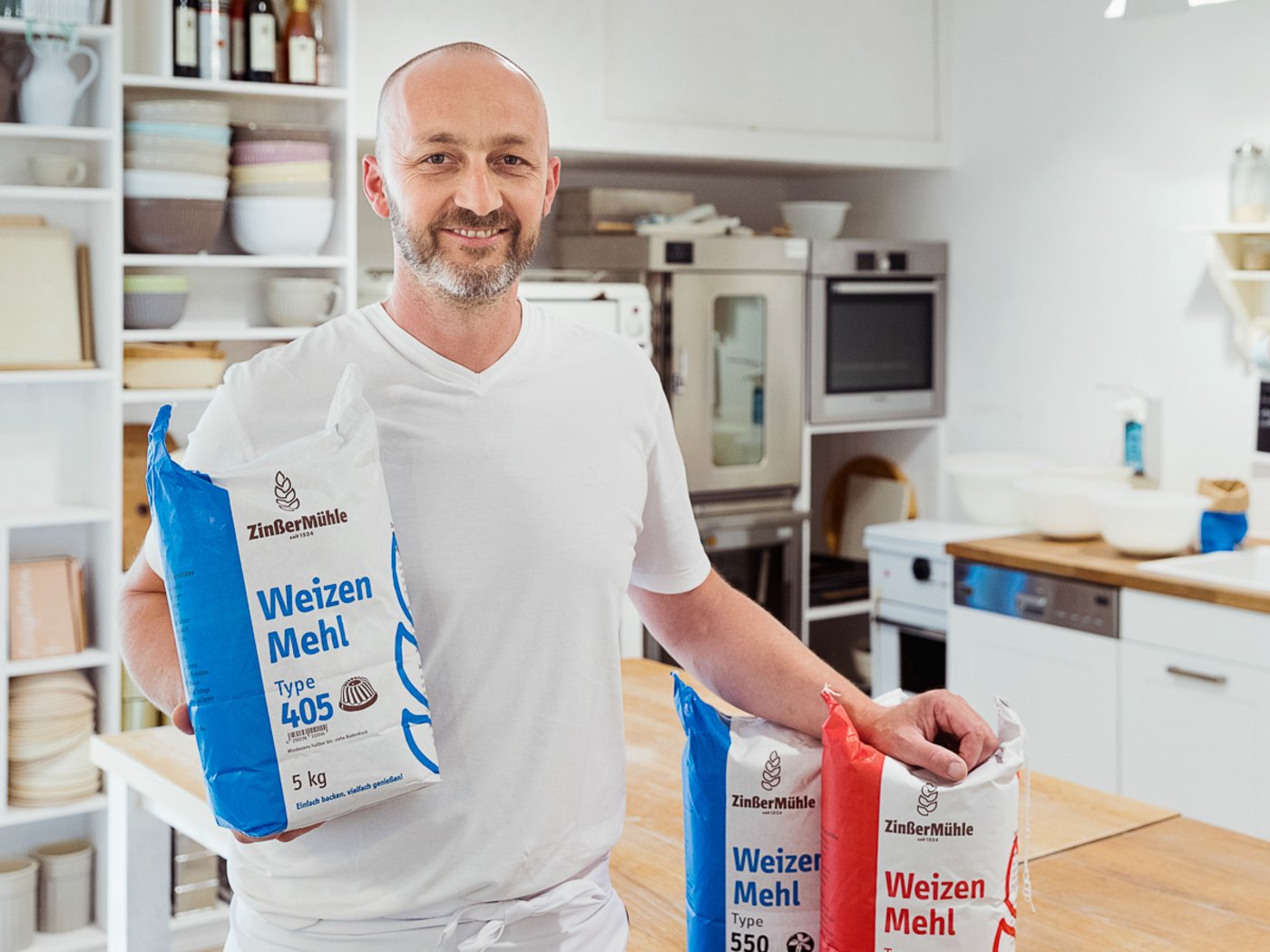 Bäcker in Backstube mit Mehl in der Hand, Portraitfoto