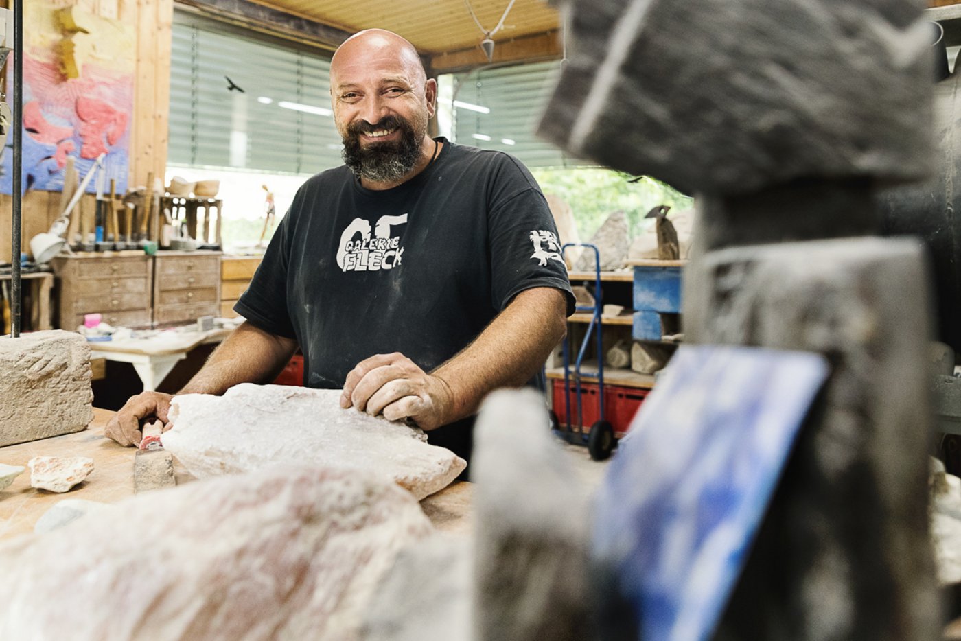 Bildhauer steht von Steinbrocken umgeben in seiner Werkstatt, Portrait
